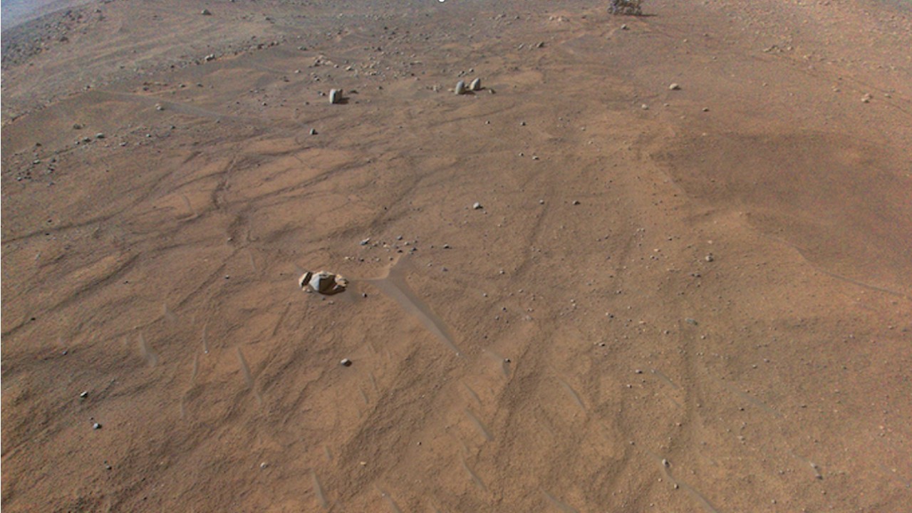 a flat rocky plain of dry regolith crossed by track-like disturbances